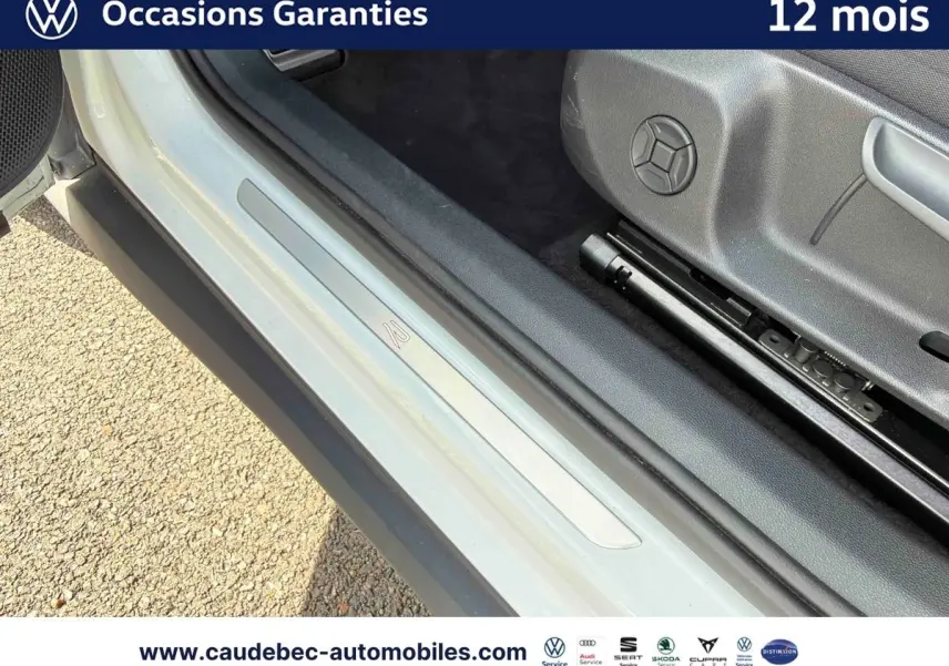 Vue rapprochée de l'encadrement de porte côté conducteur du Volkswagen T-Roc blanc, avec seuil de porte siglé R-Line.