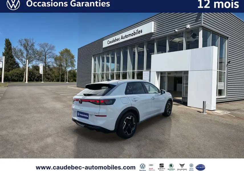 Volkswagen T-Roc blanc vue 3/4 arrière droit, avec feux LED arrière et jantes alliage noires brillantes, devant concession.