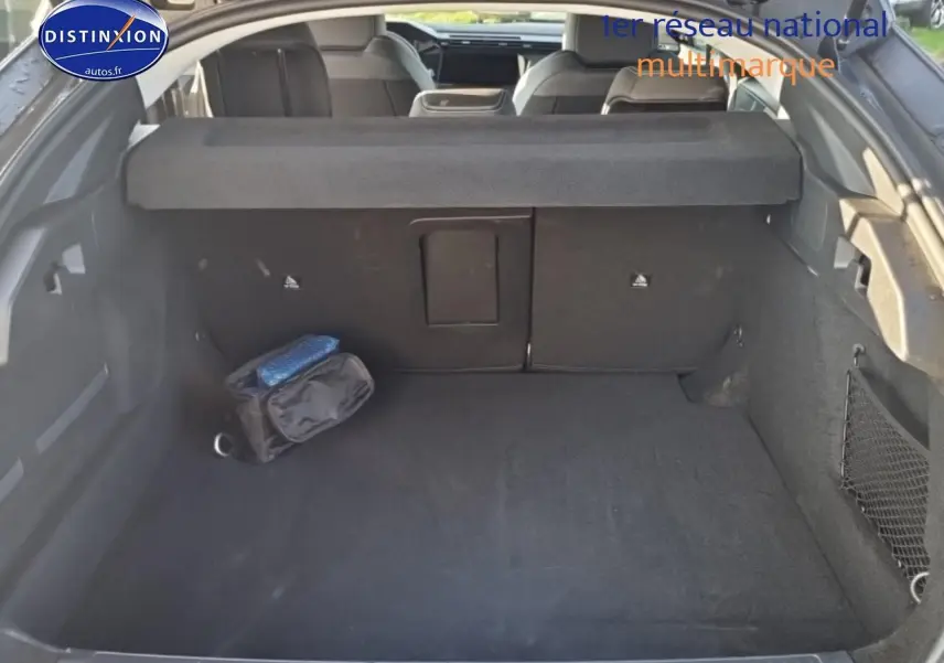 Coffre ouvert d'une Peugeot 408 Hybrid 145 allure gris sélénite, montrant l'espace de chargement et la banquette arrière.