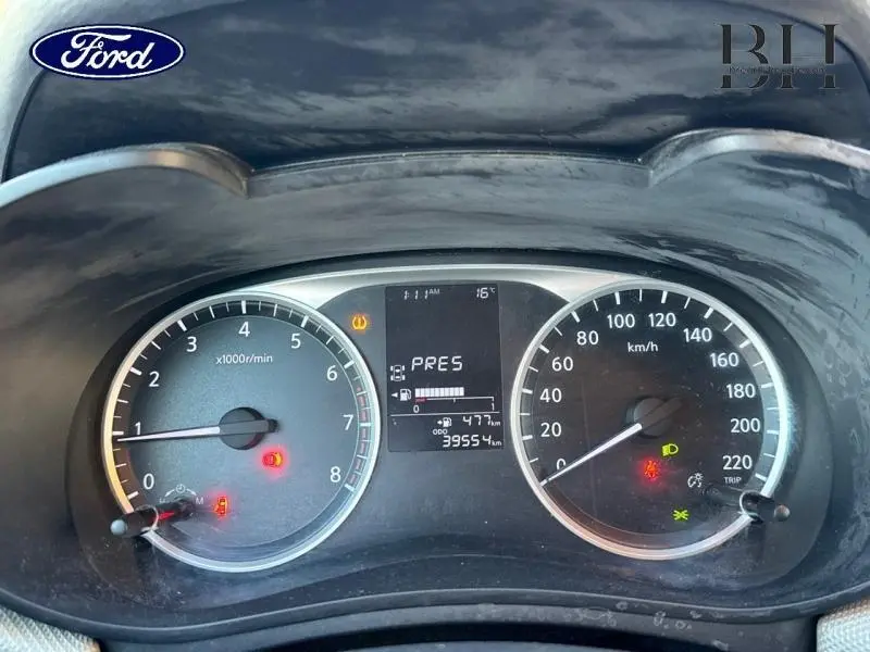 Vue rapprochée du tableau de bord d'une Nissan Micra gris acier, affichant le compteur et les voyants allumés.