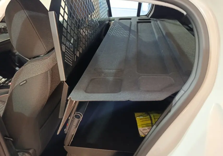 Vue intérieure côté droit du coffre de la Peugeot 208 électrique blanche avec tablette de rangement relevée.