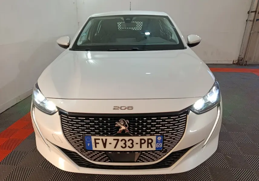 Vue de face d'une Peugeot 208 électrique Active Business blanche avec phares allumés et calandre noire distinctive.