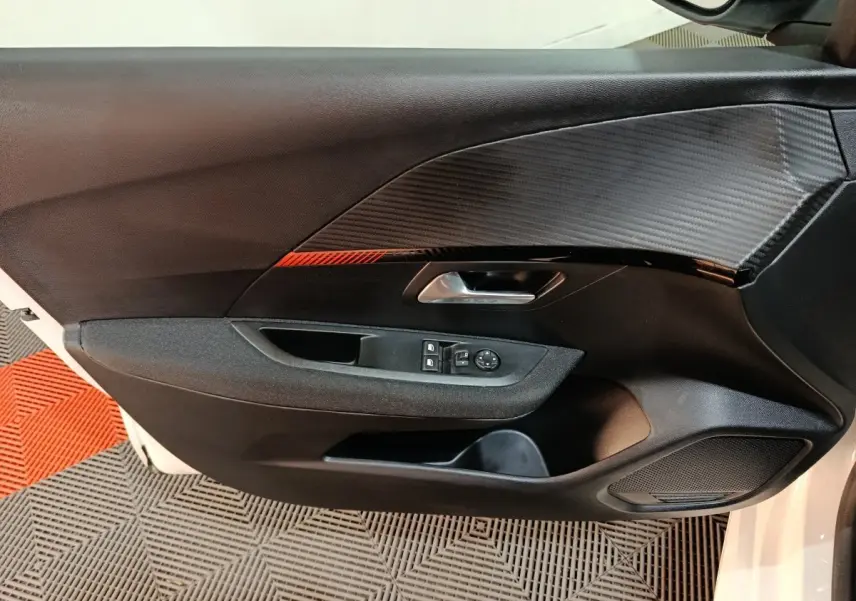 Vue rapprochée de la porte intérieure côté gauche de la Peugeot 208 électrique blanche avec insert décoratif noir et rouge.