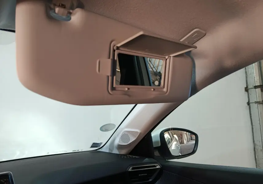 Intérieur de la Peugeot 208 électrique blanc, vue côté passager avec pare-soleil et miroir de courtoisie ouvert.
