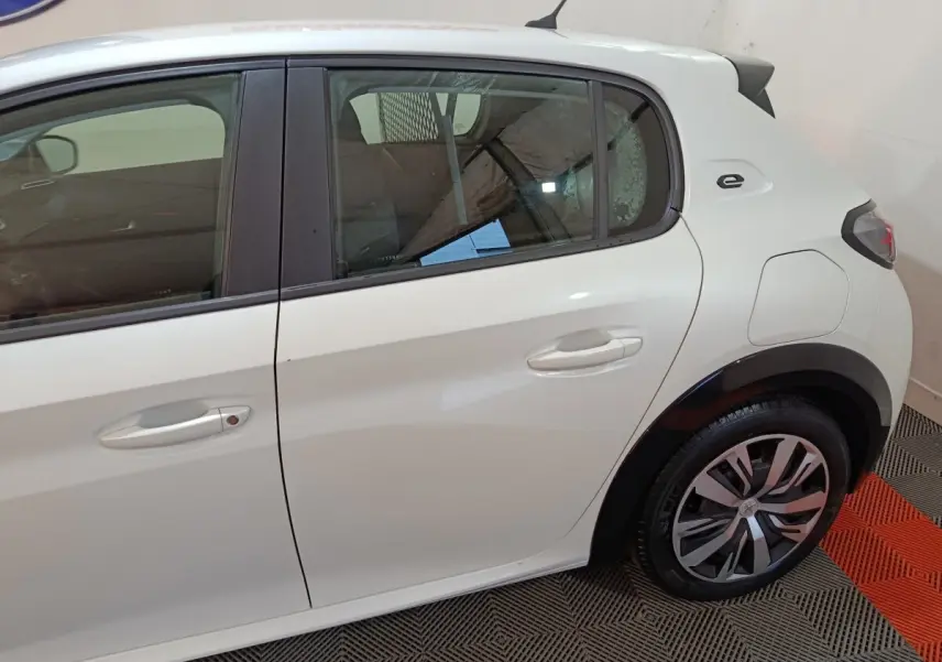 Vue latérale droite d'une Peugeot 208 électrique blanche avec logo "e" distinctif près de la porte arrière.