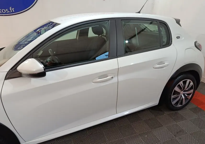 Vue de profil côté gauche d'une Peugeot 208 électrique Active Business blanche avec jantes spécifiques et logo "e" arrière.