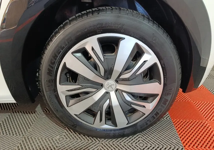 Gros plan sur la roue avant droite de la Peugeot 208 électrique blanche, avec jante en alliage au design moderne.