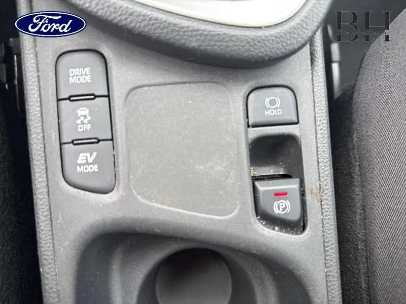 Gros plan sur les commandes de mode de conduite et frein à main électronique de la Toyota Yaris Cross blanche.