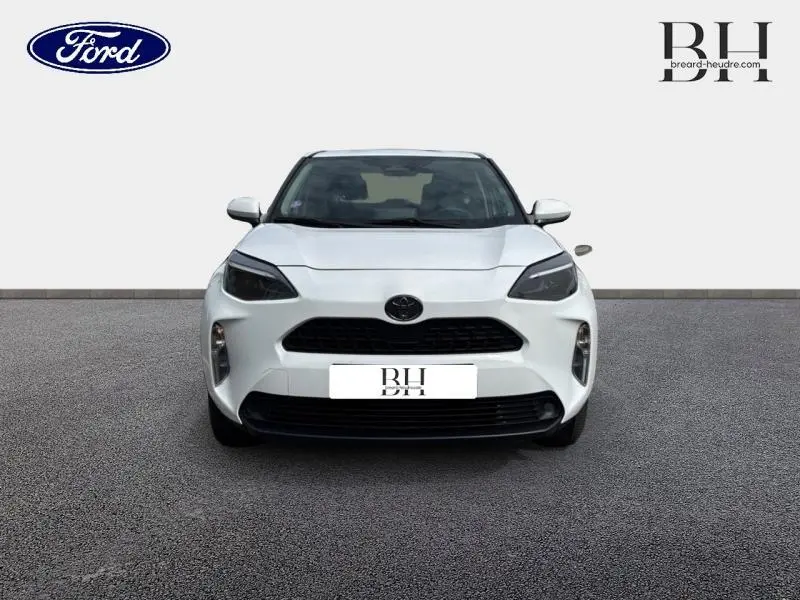 Vue frontale d'une Toyota Yaris Cross 116h Dynamic blanche, mettant en valeur sa calandre noire et ses phares effilés.