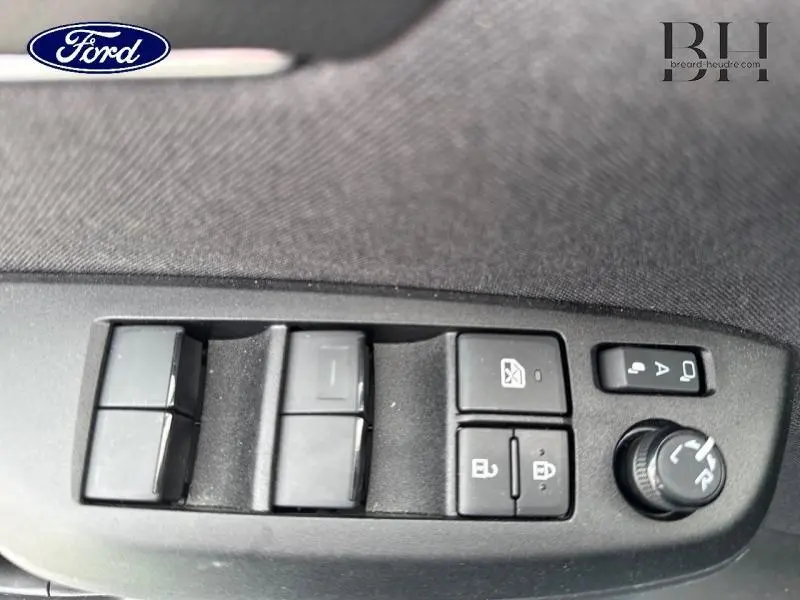 Gros plan sur les commandes des vitres et rétroviseurs côté gauche d'une Toyota Yaris Cross blanche.