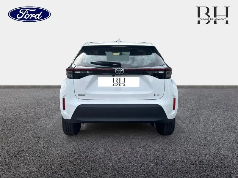 Vue arrière d'une Toyota Yaris Cross 116h Dynamic blanche, avec feux arrière en bandeau et pare-chocs noir.