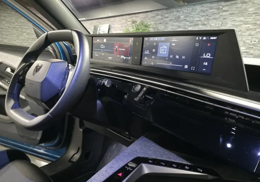 Vue intérieure côté conducteur du Peugeot 5008 bleu 2025, avec tableau de bord numérique panoramique et volant compact cuir.