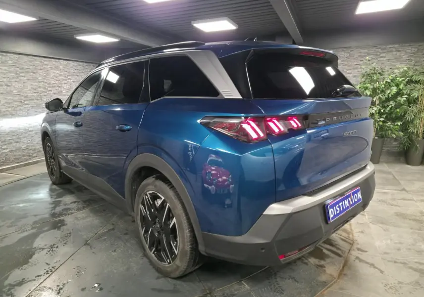 Peugeot 5008 bleu métallisé en 3/4 arrière droit, feux arrière LED à 3 griffes et jantes alliage 19 pouces.