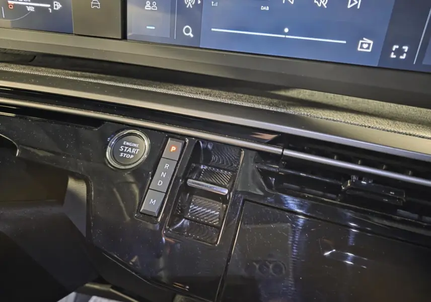 Détail de la console centrale noire laquée avec bouton start/stop et commandes de boîte automatique du Peugeot 5008 hybride 2025.