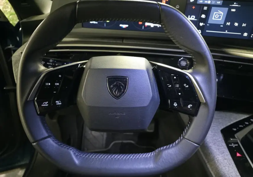 Gros plan sur le volant noir en cuir du Peugeot 5008 2025 avec commandes intégrées et logo central lion.
