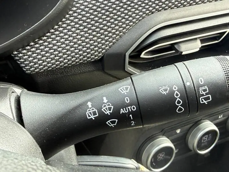 Gros plan sur la commande des essuie-glaces du DACIA JOGGER 2025, avec détails des symboles blancs sur fond noir.