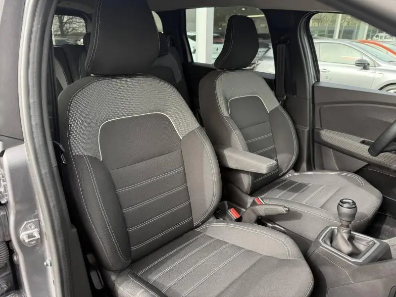Vue intérieure côté conducteur du Dacia Jogger 2025, montrant les sièges tissu gris et la boîte manuelle.