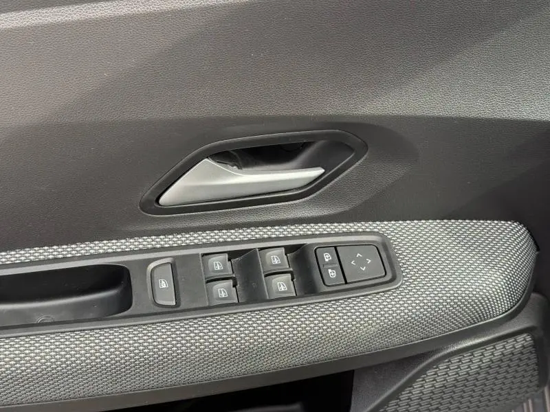 Gros plan sur la commande des vitres électriques et la poignée intérieure côté conducteur du Dacia Jogger gris Schiste métallisé.