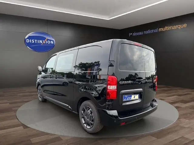 Vue 3/4 arrière droite d’un Citroën Jumpy noir 2025 avec vitres arrière opaques et jantes foncées, en showroom.