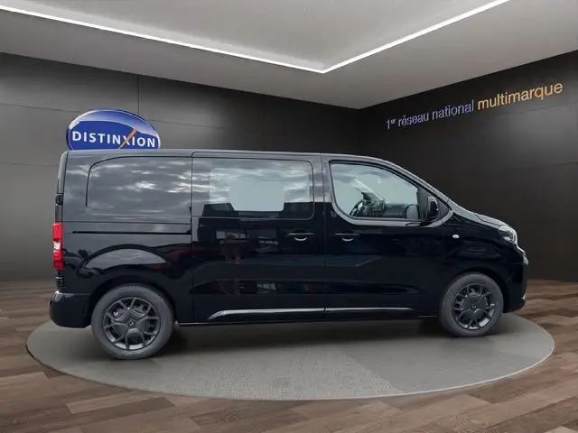 Vue latérale droite d'un Citroën Jumpy noir 2025, avec vitres avant et arrière, sur un podium intérieur.