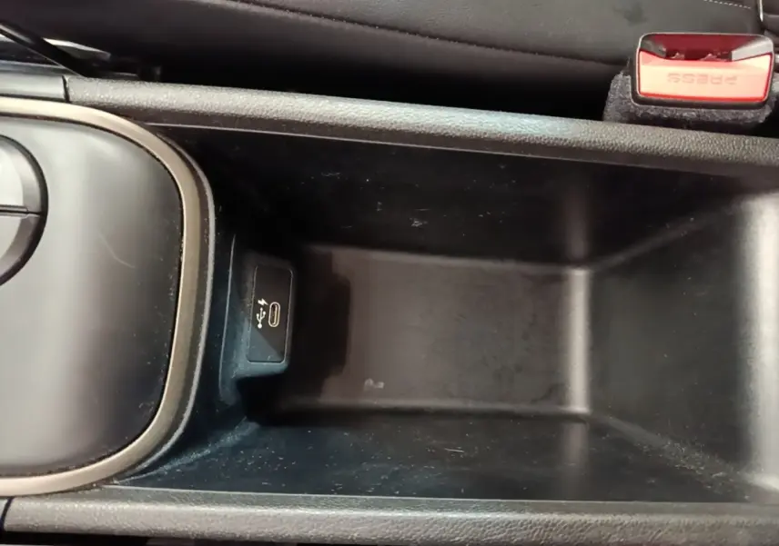 Vue rapprochée de la console centrale noire du MINI Countryman Cooper SE avec port USB-C et bouton de frein à main rouge.