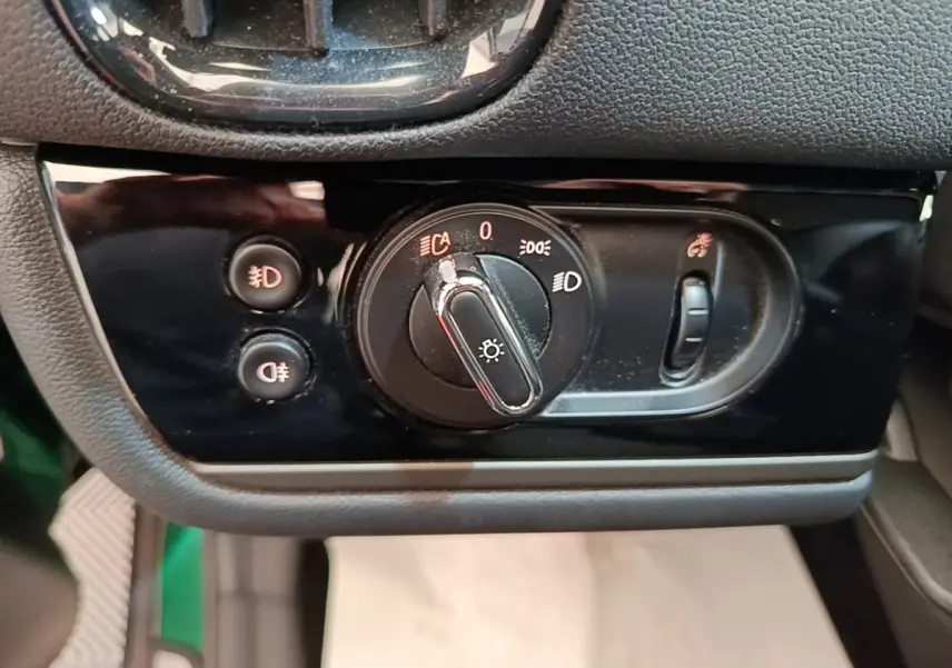 Gros plan sur la commande des phares et antibrouillards du tableau de bord noir d'une MINI Countryman gris clair.
