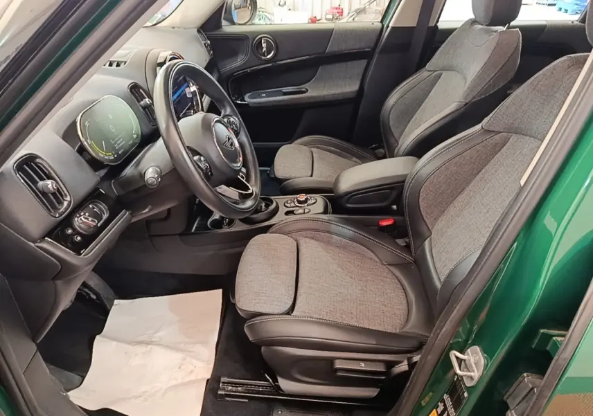 Vue intérieure côté conducteur d'une MINI Countryman hybride rechargeable avec sièges tissu gris et volant cuir noir.