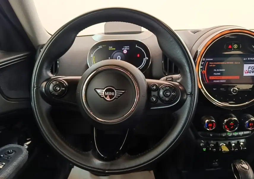 Vue intérieure centrée sur le volant cuir noir et le tableau de bord digital du MINI Countryman hybride gris clair.
