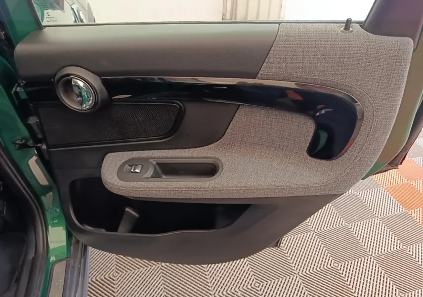 Vue intérieure côté gauche de la porte avant d'une MINI Countryman gris clair avec habillage tissu et plastique noir brillant.