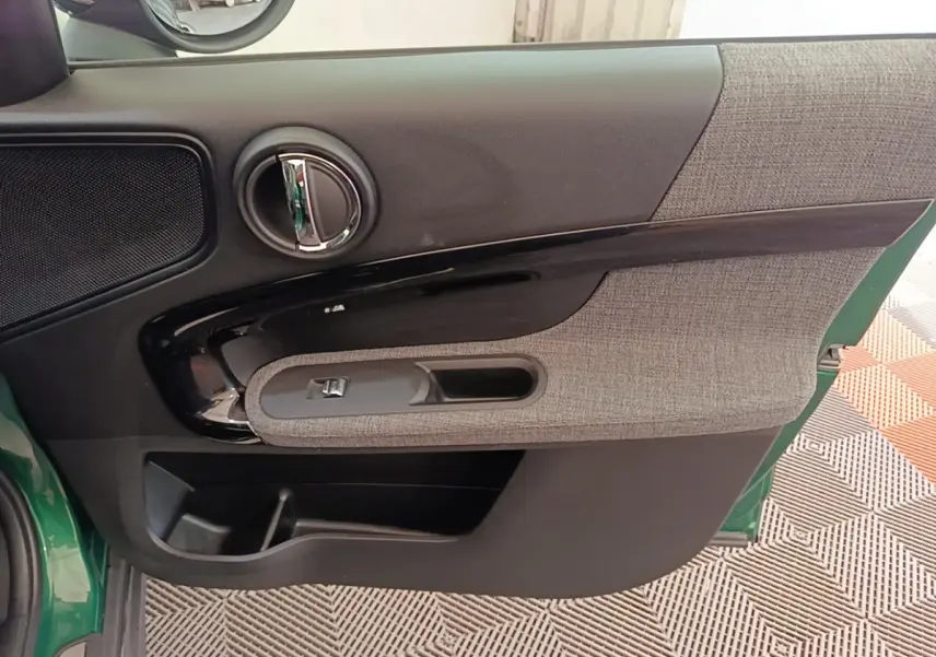 Vue intérieure de la porte avant gauche d'une MINI Countryman 2021, avec garniture tissu gris et plastique noir brillant.
