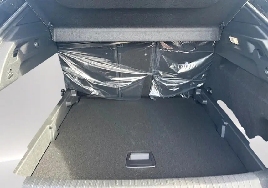 Vue intérieure du coffre spacieux du Peugeot 3008 gris Artense, avec banquette arrière protégée par un film plastique.
