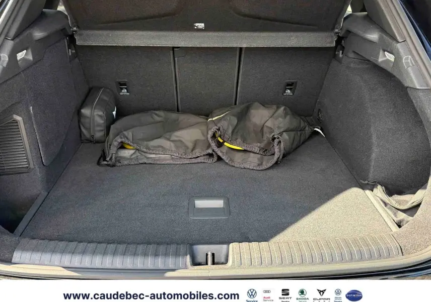 Coffre ouvert de la CUPRA Terramar noire, vue de l'arrière montrant un espace de chargement propre avec housses noires posées.