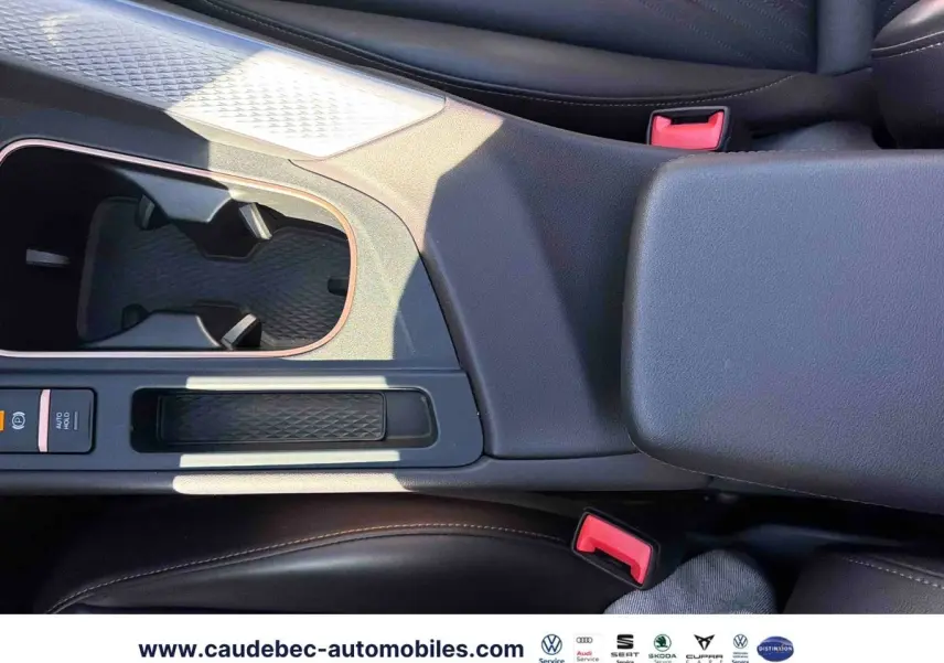 Vue rapprochée de la console centrale noire avec accoudoir et porte-gobelets du CUPRA Terramar 2024.