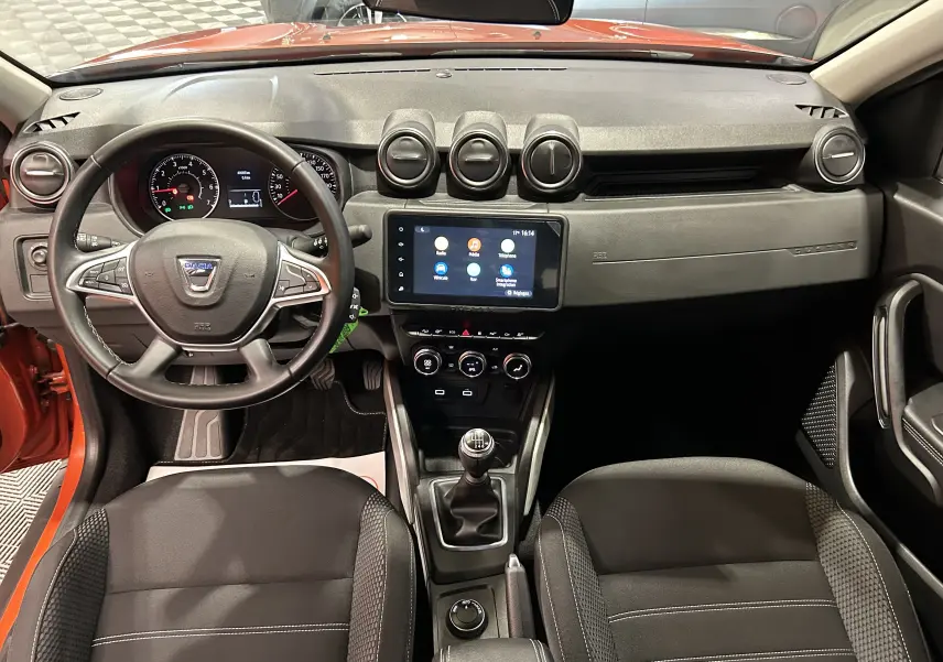 Vue intérieure avant du Dacia Duster 2022 orange Arizona, tableau de bord avec écran tactile et volant multifonction.