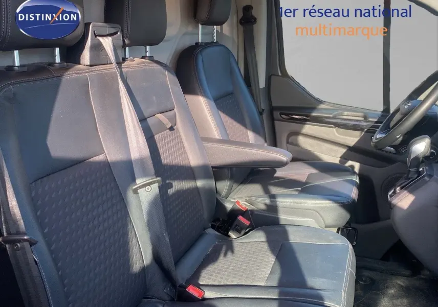 Intérieur du Ford Transit Custom gris magnetic, vue côté conducteur sur les sièges avant en cuir noir avec accoudoir.
