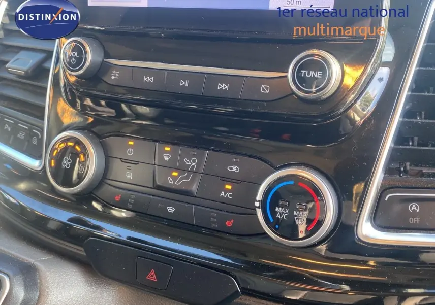 Gros plan sur la console centrale noire du Ford Transit Custom gris, montrant les commandes de climatisation et multimédia.