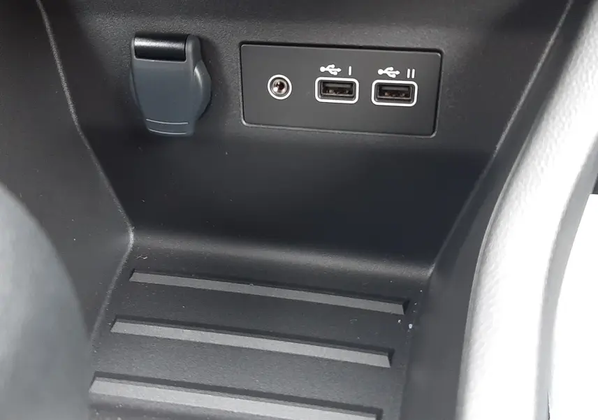 Gros plan sur la console centrale noire avec deux ports USB et une prise 12V dans une Renault Clio V hybride.
