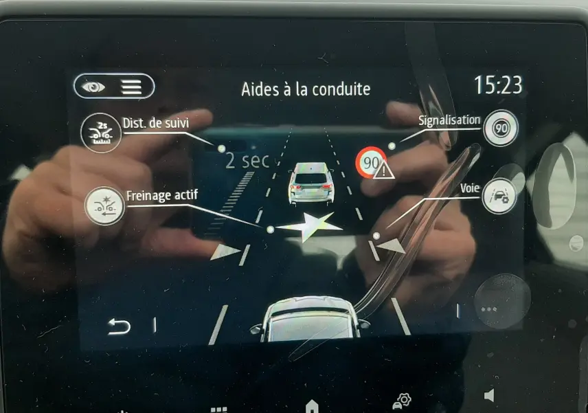 Écran tactile intérieur de la Renault Clio V gris schiste montrant l’aide à la conduite avec suivi de distance et signalisation.