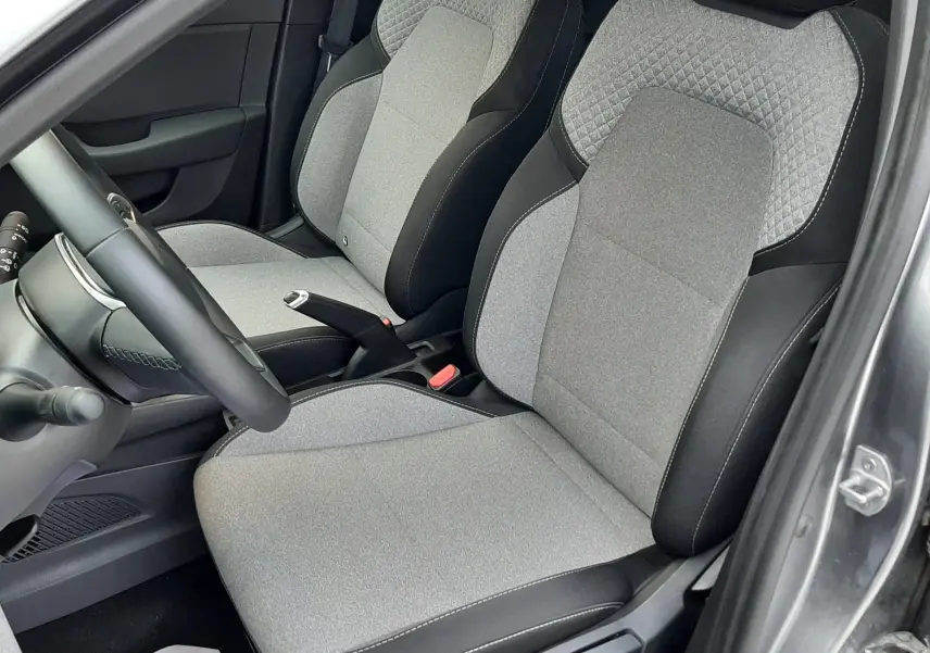 Vue intérieure côté conducteur de la Renault Clio V E-Tech gris schiste, sièges tissu gris avec surpiqûres noires.