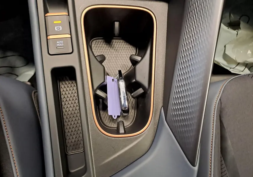 Vue rapprochée de la console centrale du CUPRA TERRAMAR 2025 avec porte-gobelets et bouton frein à main électronique.