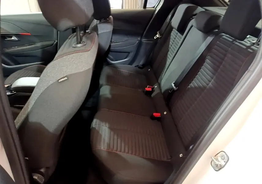 Vue intérieure côté droit sur la banquette arrière noire avec surpiqûres rouges d'une Peugeot 208 Electrique Active Business blanche.