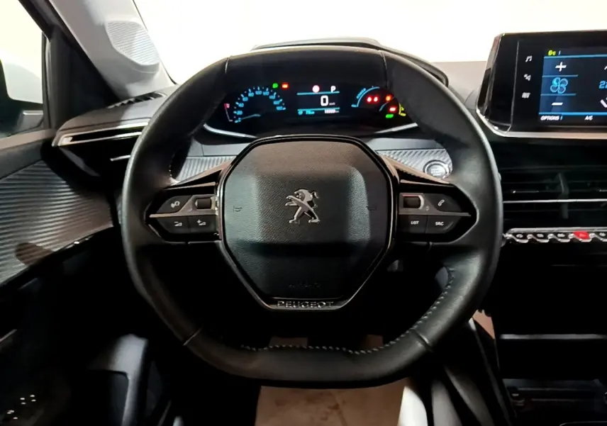Vue centrée sur le volant cuir noir du Peugeot 208 électrique, avec tableau de bord numérique et écran tactile visible.