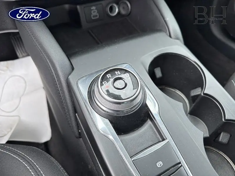 Gros plan sur la molette de boîte automatique et les porte-gobelets du Ford Kuga noir Agate 2023, intérieur moderne.