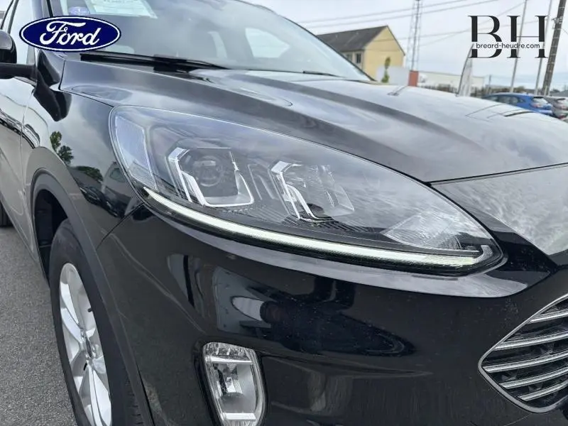 Gros plan sur le phare avant gauche du Ford Kuga noir Agate métallisé avec calandre et antibrouillard visibles.