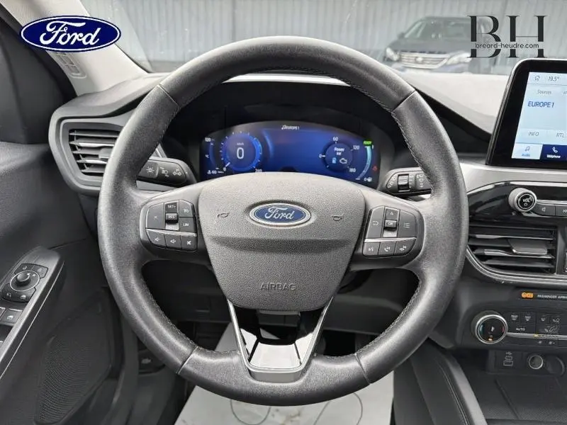 Vue centrée sur le volant cuir multifonction du Ford Kuga 2023 avec tableau de bord numérique et écran tactile.