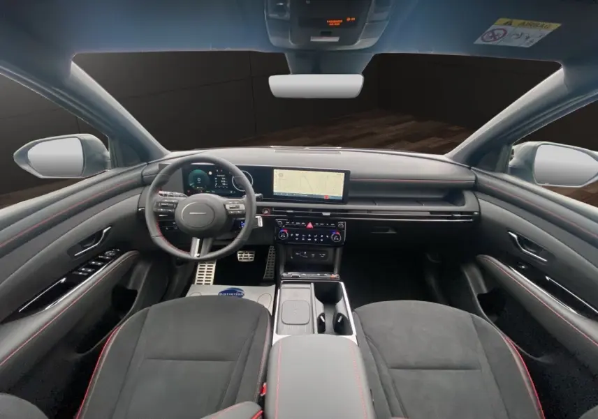 Vue intérieure avant du Hyundai Tucson 1.6 Hybrid gris foncé, avec tableau de bord numérique et écran tactile central.