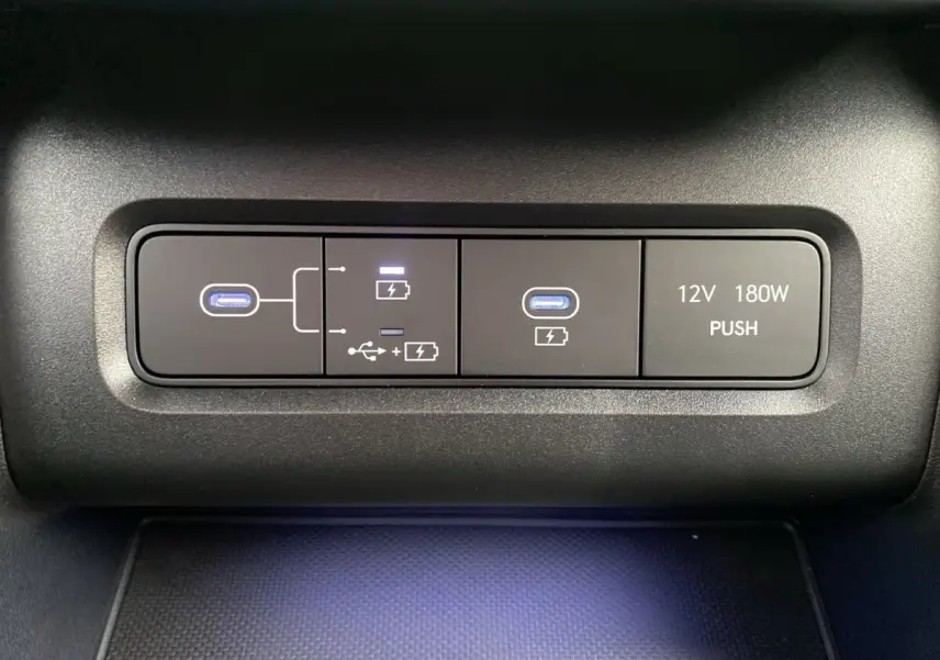 Gros plan sur les ports USB-C et prise 12V avec éclairage bleu dans l’habitacle du Hyundai Tucson gris foncé.