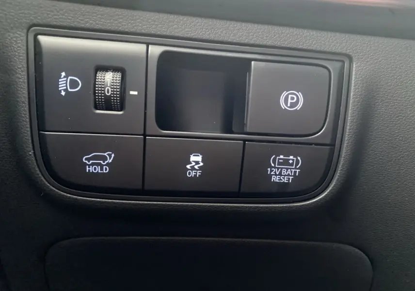 Gros plan sur les commandes noires du tableau de bord du Hyundai Tucson 1.6 Hybrid N Line, avec boutons éclairés blancs.