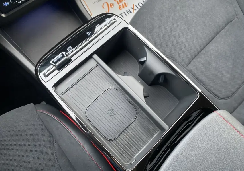 Vue rapprochée de la console centrale noire du Hyundai Tucson 1.6 Hybrid N Line avec porte-gobelets et chargeur sans fil.