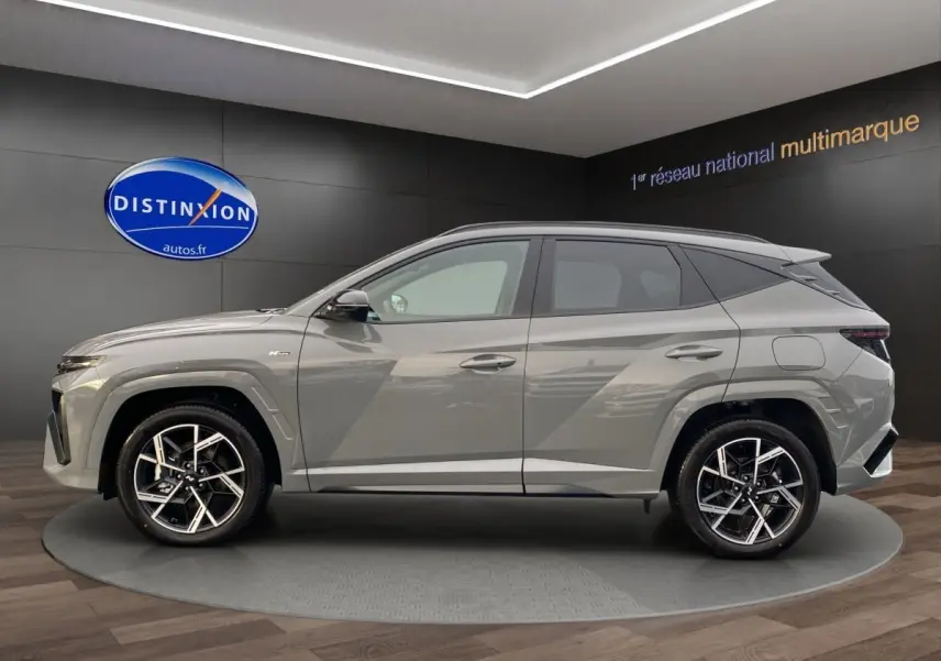 Profil côté gauche d'un Hyundai Tucson gris foncé 2026 N Line Creative en showroom avec jantes alliage noires et argentées.